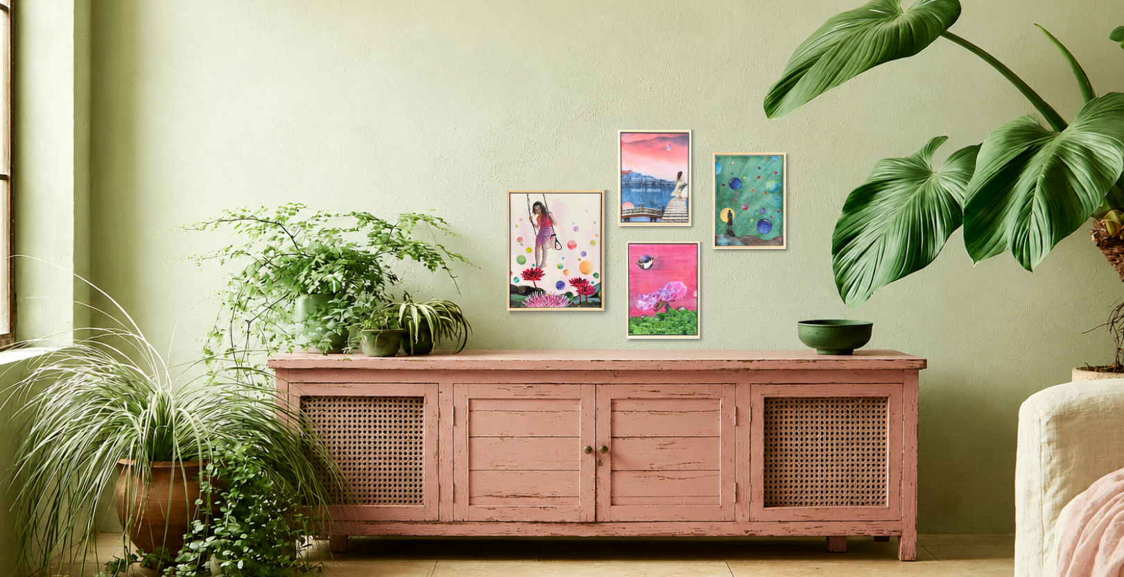 Four original collage paintings from the Waiting for me collection, presented in a room with a pink wooden sideboard cabinet agains a green wall and potted plants.
