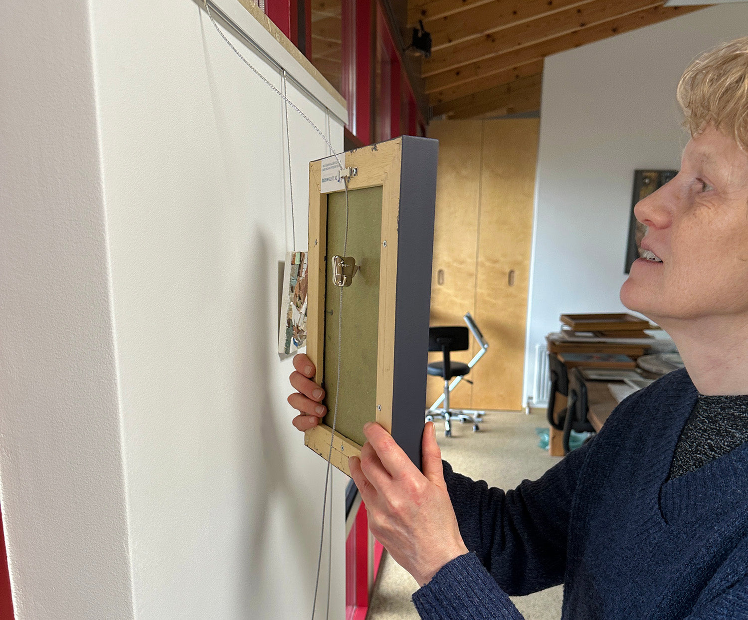 Maartje hanging an original mosaic artwork. Each piece arrives ready to hang, no framing needed.