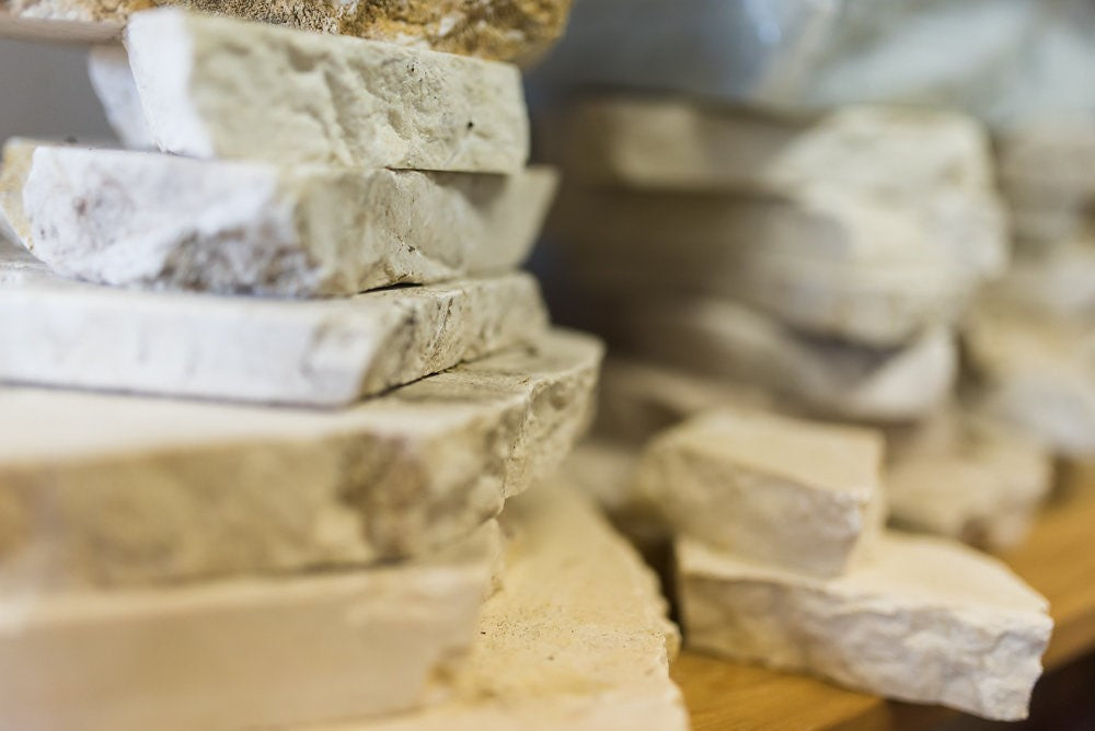Stacked pieces of white marble on a wooden shelf, suggesting hidden layers beneath a seemingly solid surface, echoing the blog’s metaphor of emotional layers.